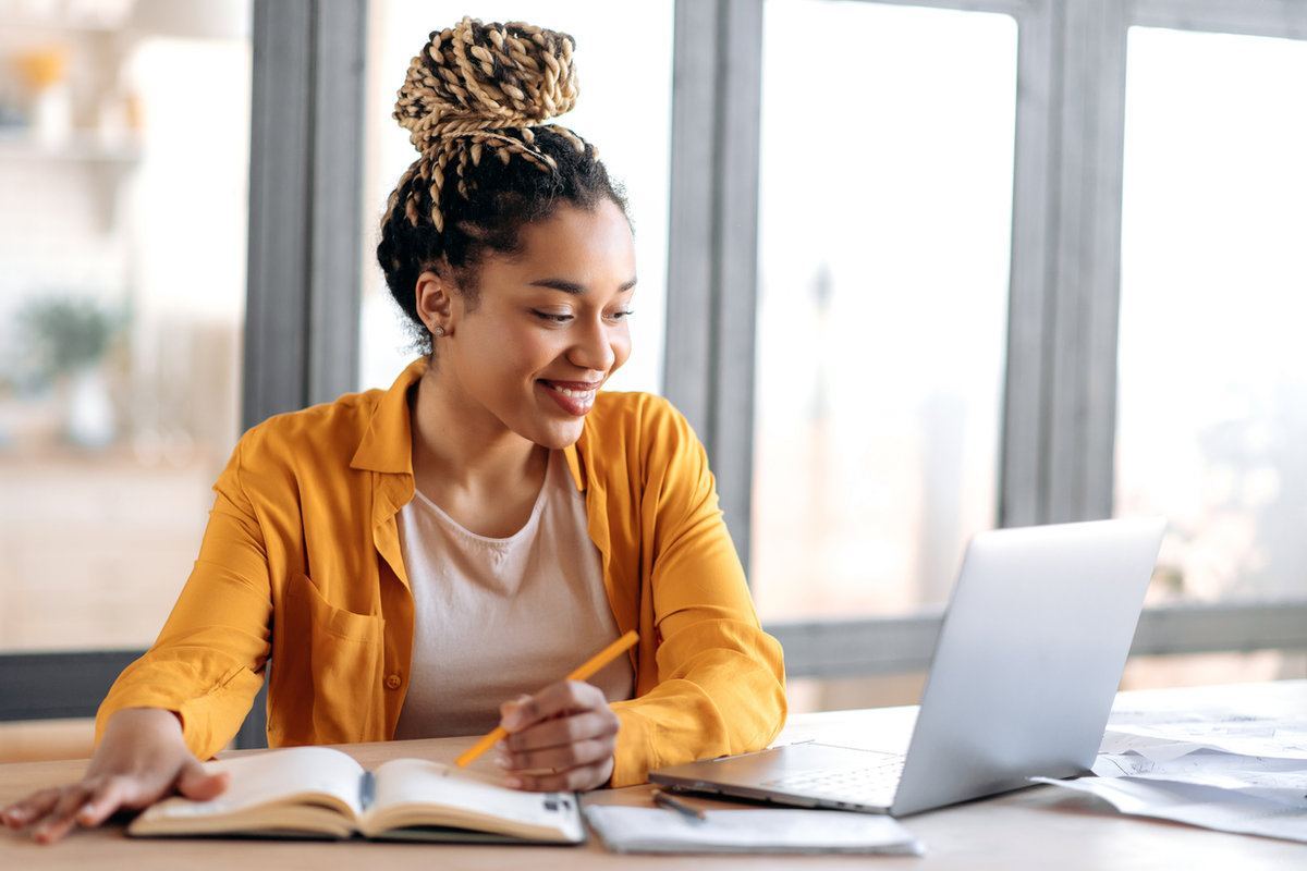 Student smiling while studying at a laptop